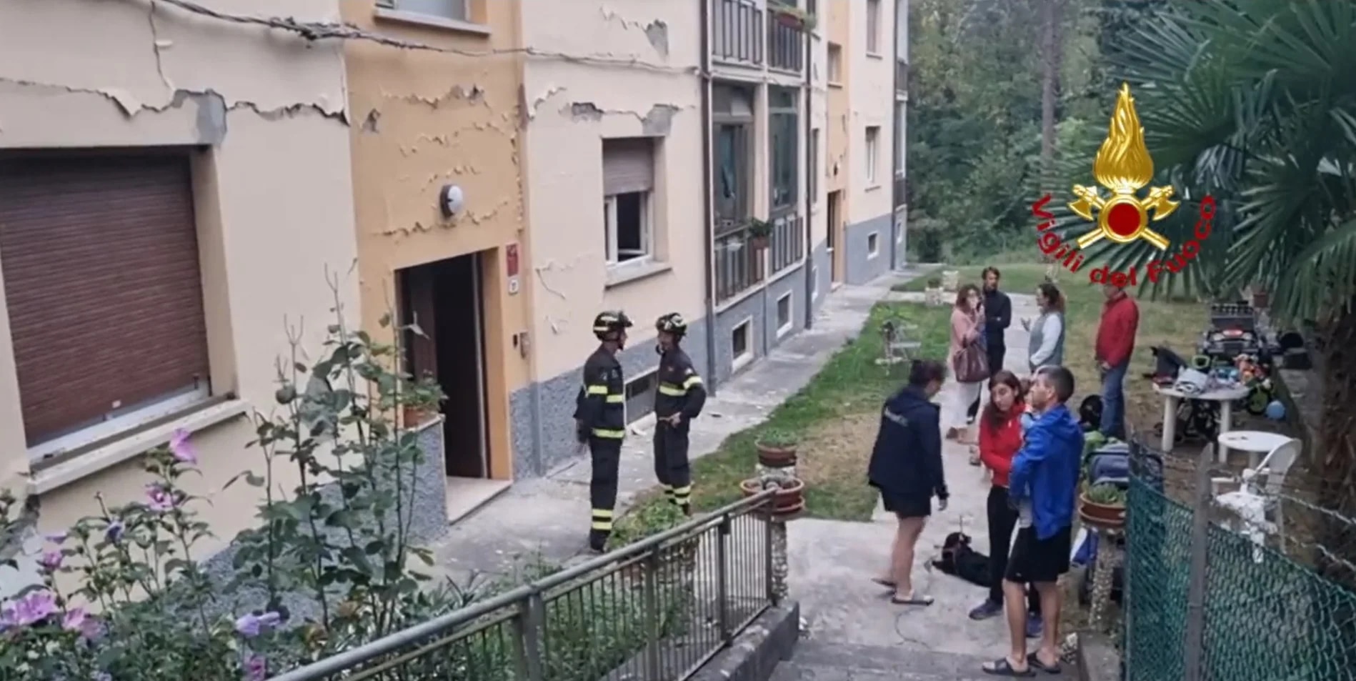 Residentes de un edificio observan algunas grietas causadas por el sismo (Vigili del Fuoco)