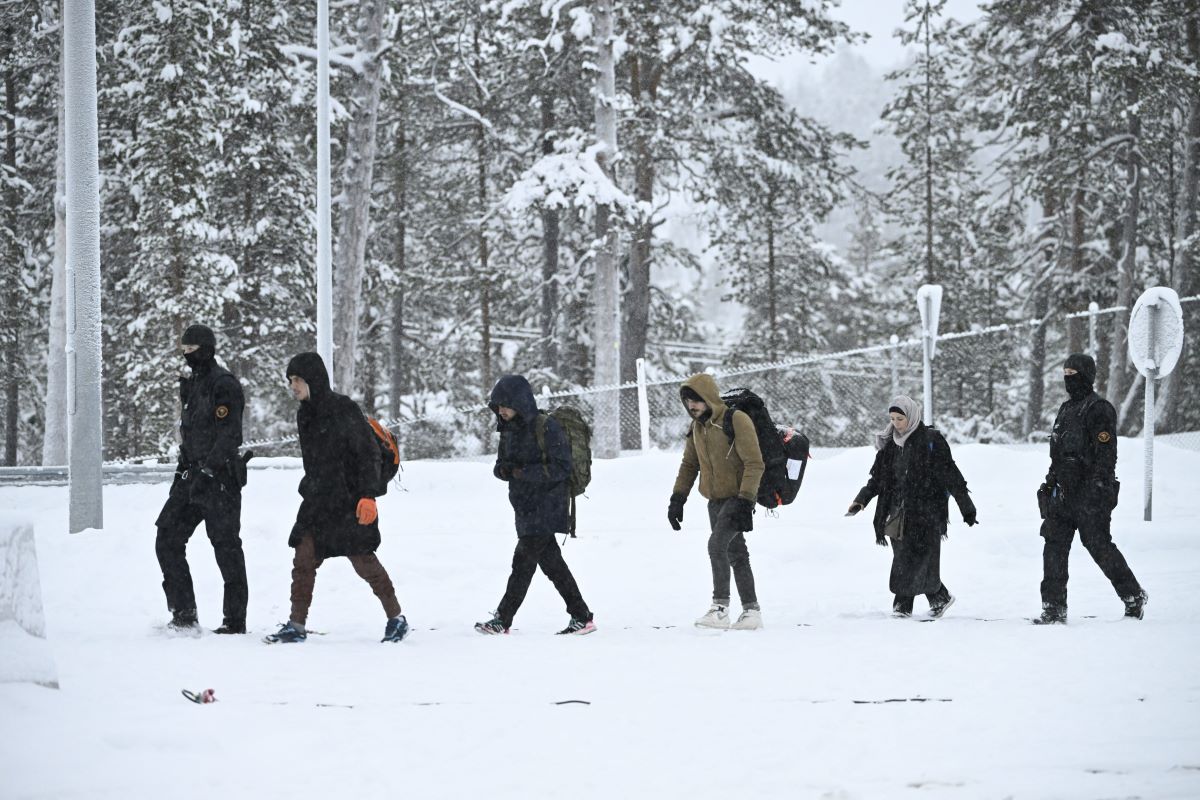 Agentes de la guardia fronteriza finlandesa escoltan a los migrantes a su llegada a la estación fronteriza de Raja-Jooseppi con Rusia en Inari, norte de Finlandia, el 25 de noviembre de 2023. (Foto de EMMI KORHONEN/Lehtikuva/AFP vía Getty Images)