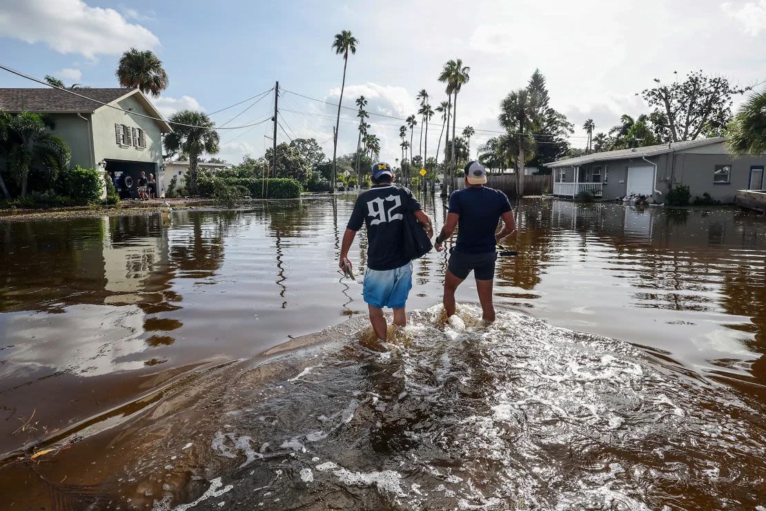 Thomas Chaves, a la izquierda, y Vinny Almeida caminan a través de las aguas de inundación del huracán Helene en un intento de llegar a la casa de la madre de Chaves en el vecindario de Shore Acres el viernes 27 de septiembre de 2024, en St. Petersburg, Florida.